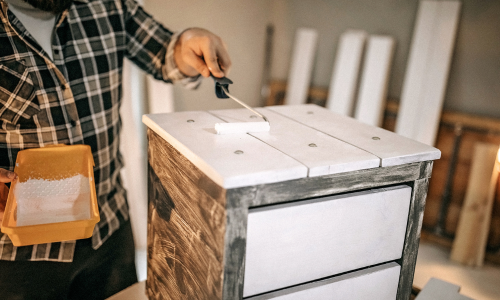 Man painting wood nightstand white