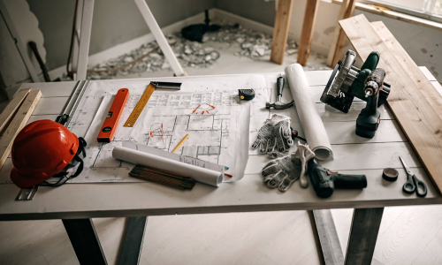 Contractors table with tools and blueprints spread across it